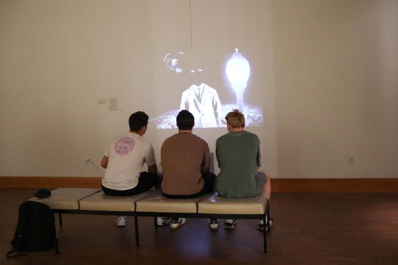 a group of people sitting on a bench looking at a projector screen