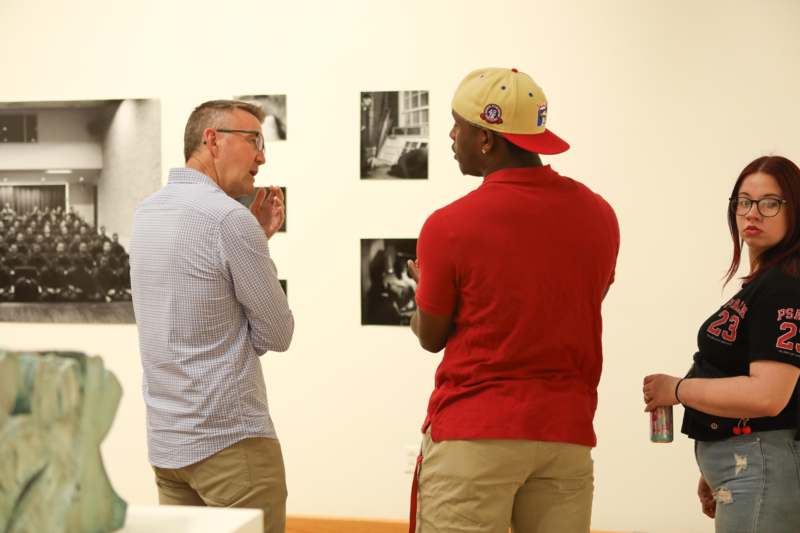 a group of men standing in front of a wall with pictures