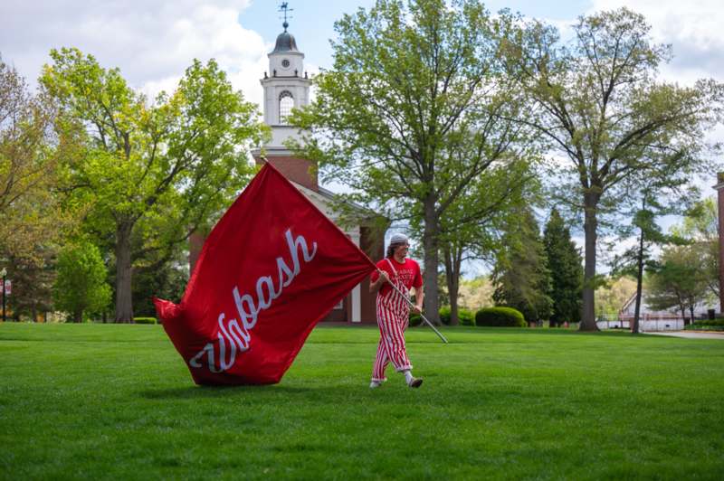Day of Giving 04.29.2026 - a person in a red and white striped outfit holding a large red flag