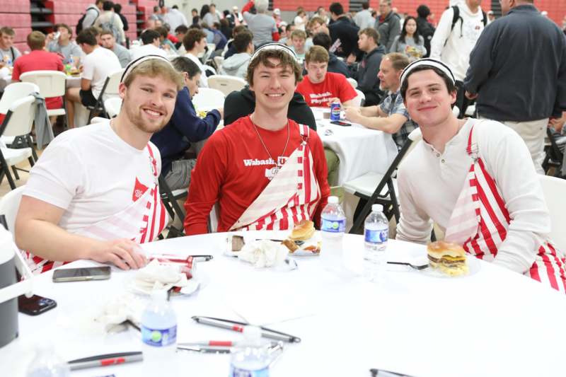 a group of men sitting at a table with food and drinks