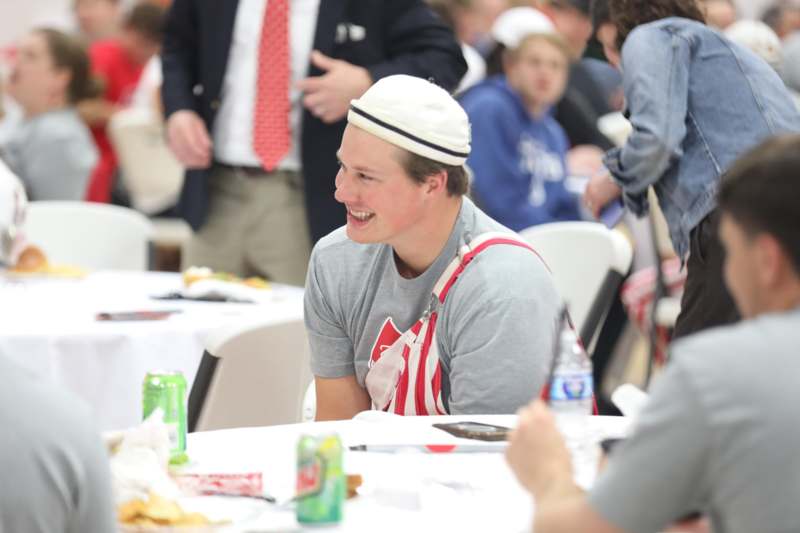 a man in a hat and apron sitting at tables