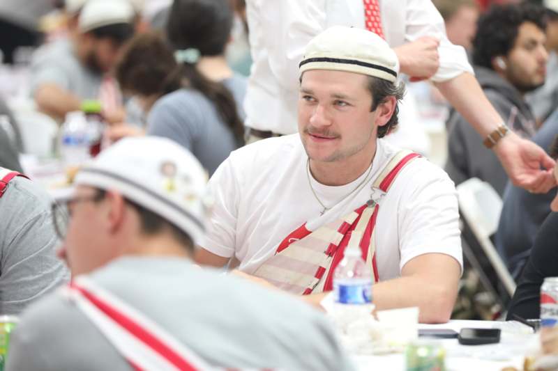 a man wearing a hat and overalls sitting at a table