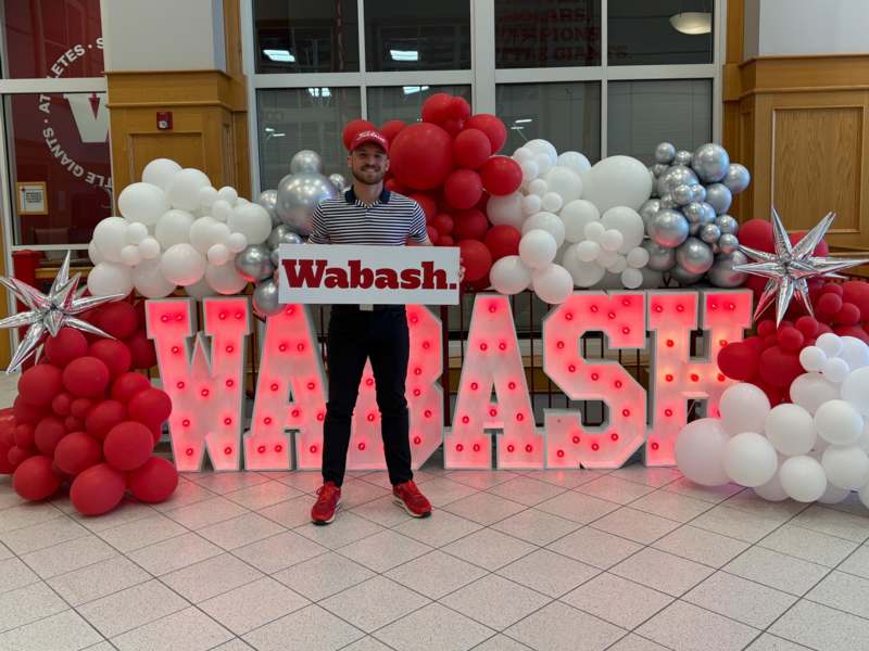 a man standing in front of a sign with balloons