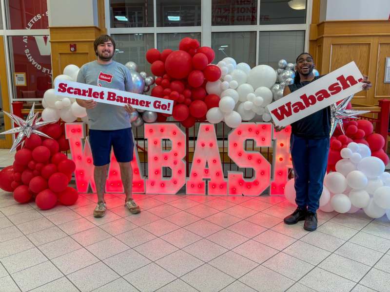 two men holding signs in front of balloons