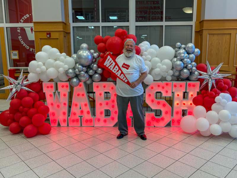 a man standing in front of a large sign with balloons