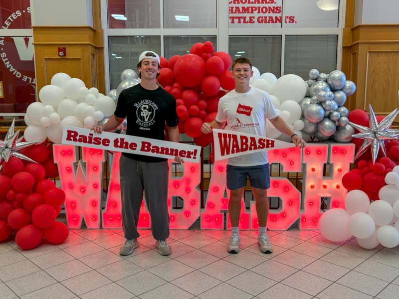 two men holding up signs in front of balloons