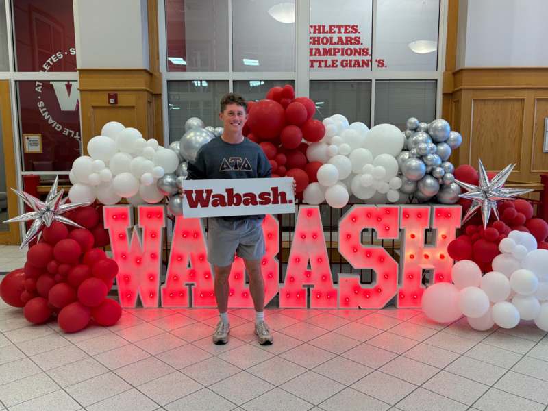 a man standing in front of a sign with balloons