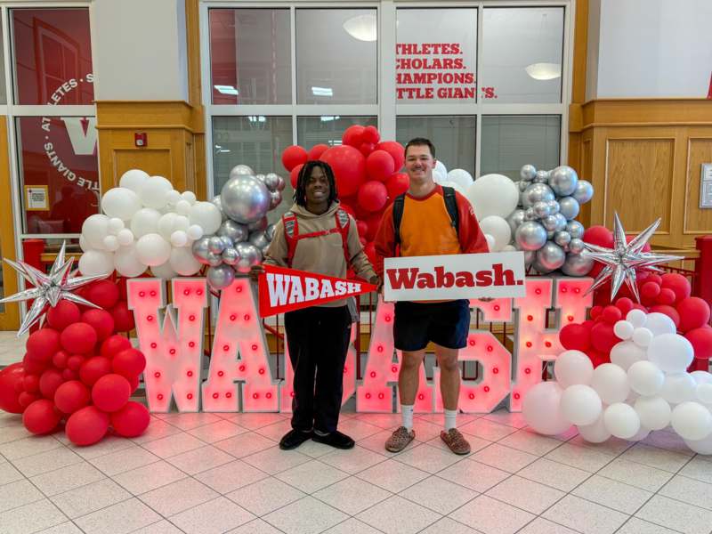 two men standing in front of balloons and signs