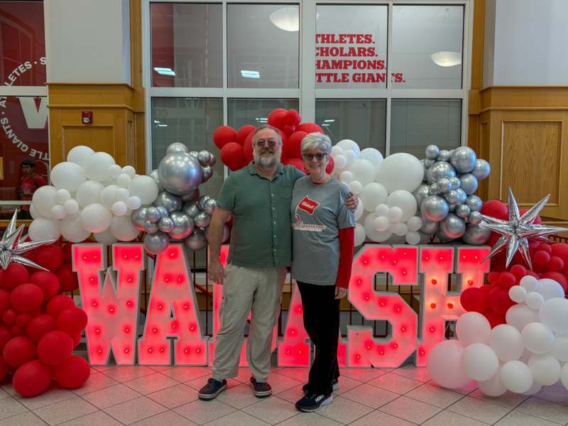 a man and woman standing in front of balloons