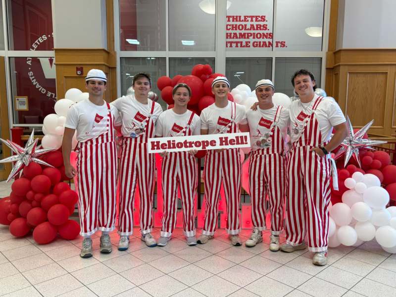 a group of men wearing striped pants and holding a sign