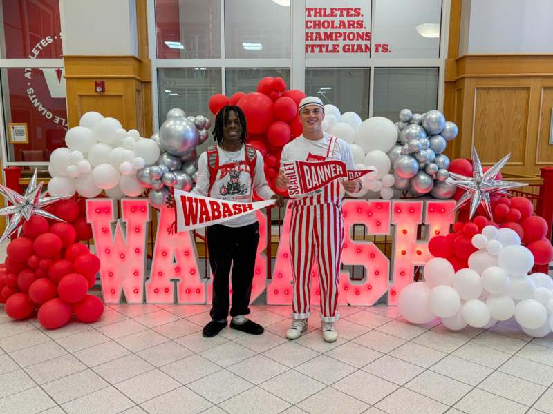 two men standing in front of a large sign