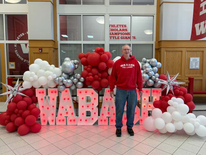 a man standing in front of a large sign with balloons