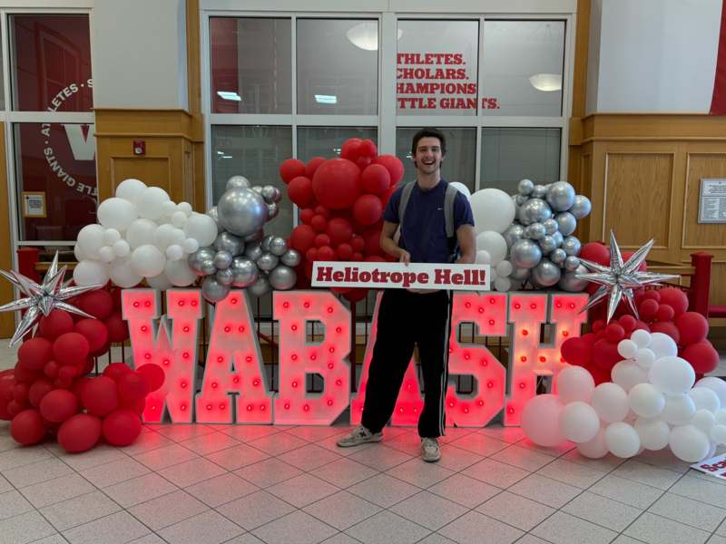 a man standing in front of a sign with balloons