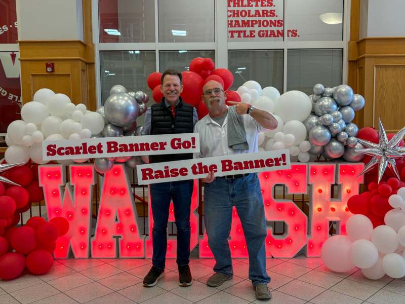 two men standing in front of a large sign