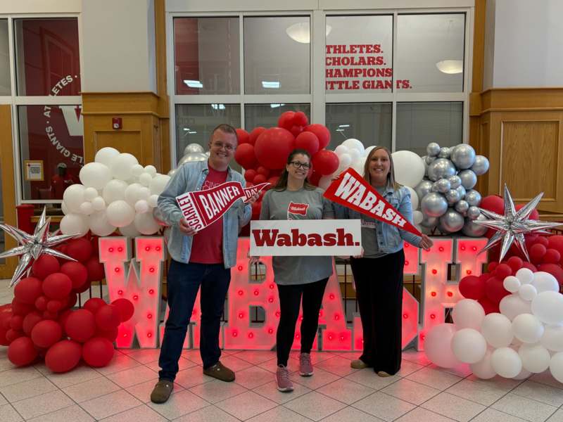 a group of people posing for a photo with balloons and letters