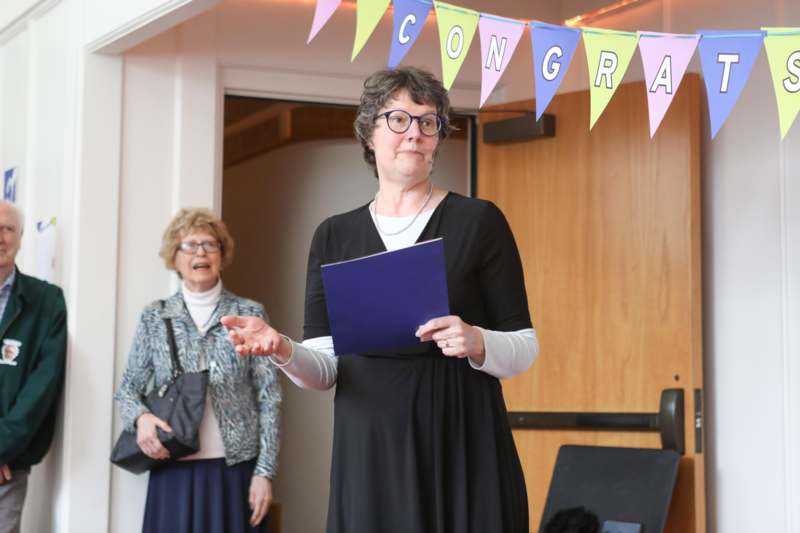 a woman in a black dress holding a blue folder