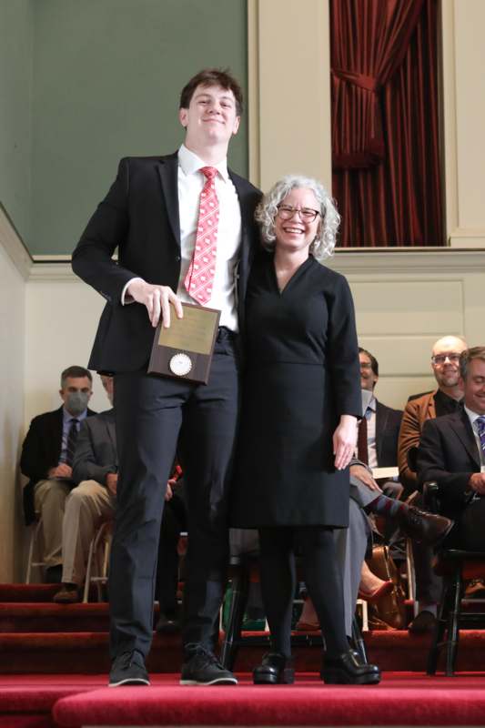 a man and woman standing on a stage with a medal
