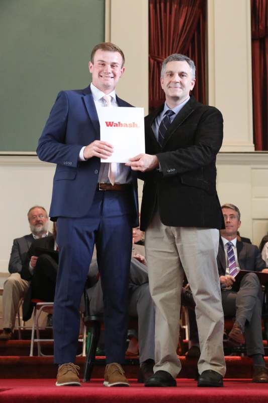 two men in suits holding a sign