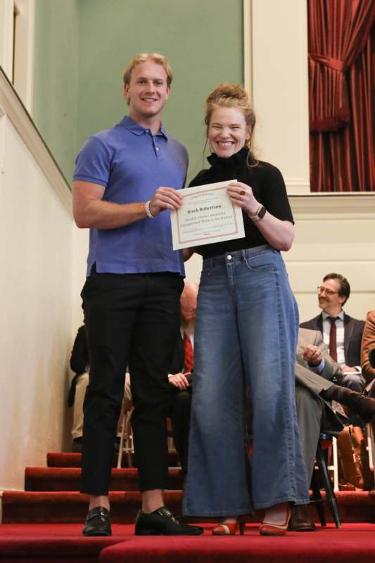 a man and woman standing on stairs holding a certificate
