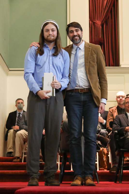 two men standing together in front of a crowd