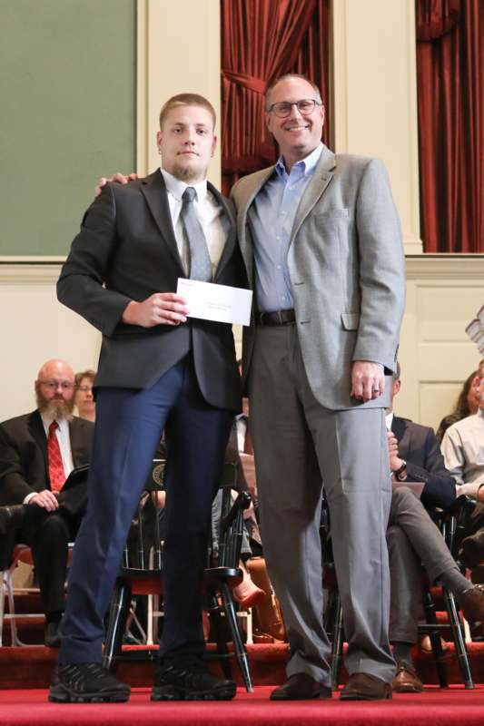 two men standing together in front of a crowd