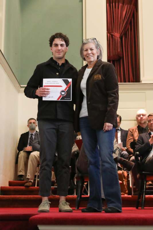 a man and woman standing on stairs with a certificate
