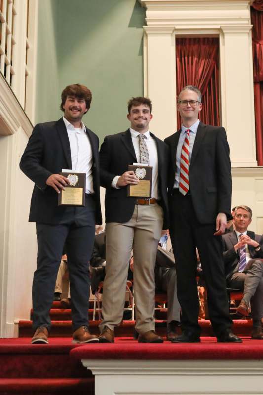 a group of men standing on stairs with awards