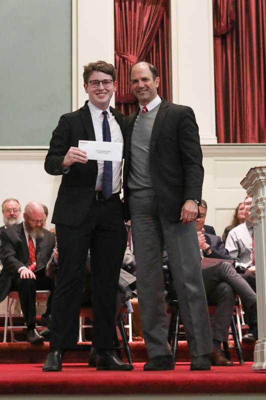 two men in suits holding a piece of paper