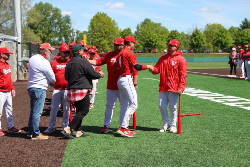a group of men shaking hands on a baseball field