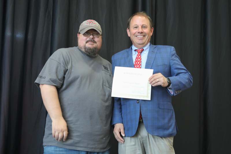a man holding a piece of paper with another man smiling