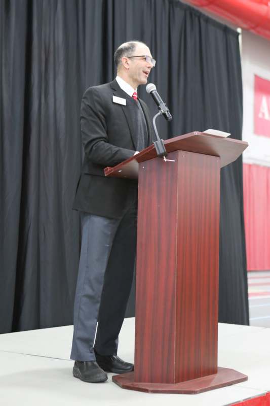 a man standing at a podium with microphones