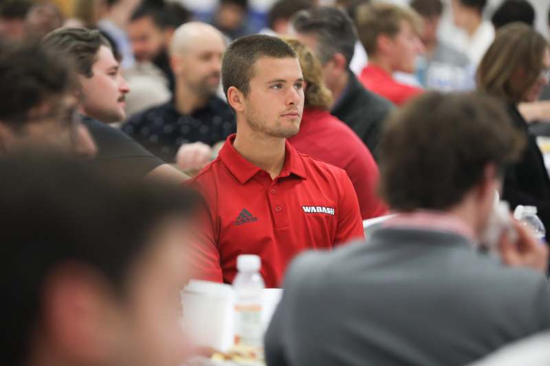 a man in a red shirt sitting at a table with other people