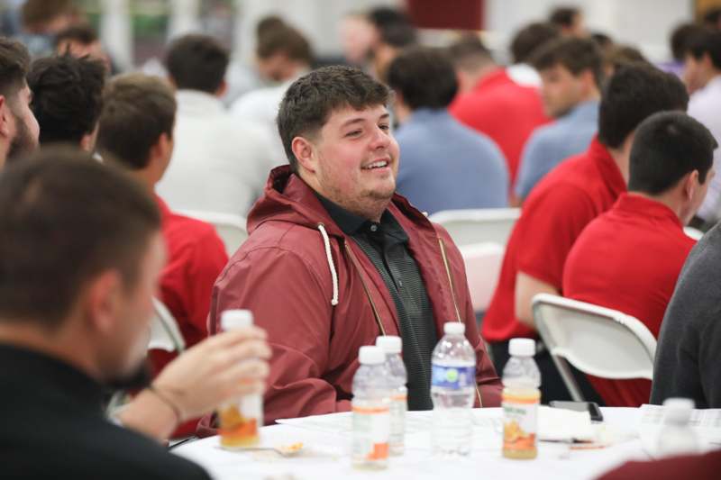 a man sitting at a table with a group of people in the background