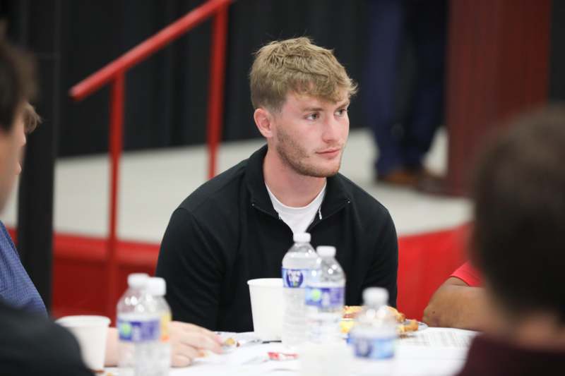 a man sitting at a table with food and water bottles