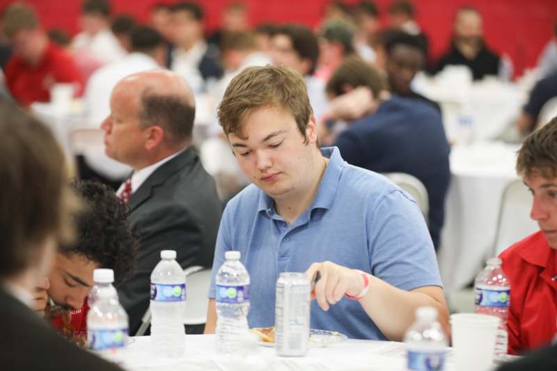 a man sitting at a table with a can of soda and water