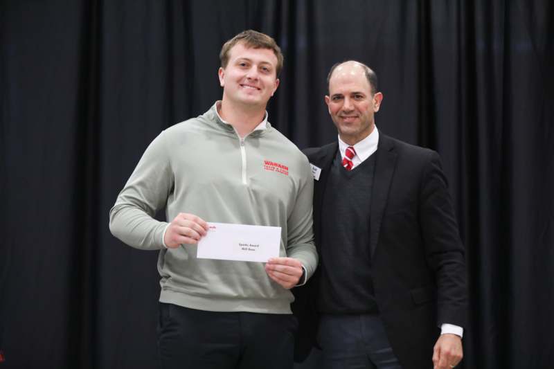 a man holding a piece of paper with another man standing next to him