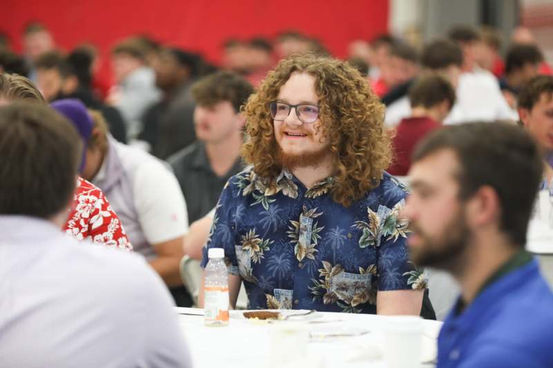 a man sitting at a table with a group of people in the background