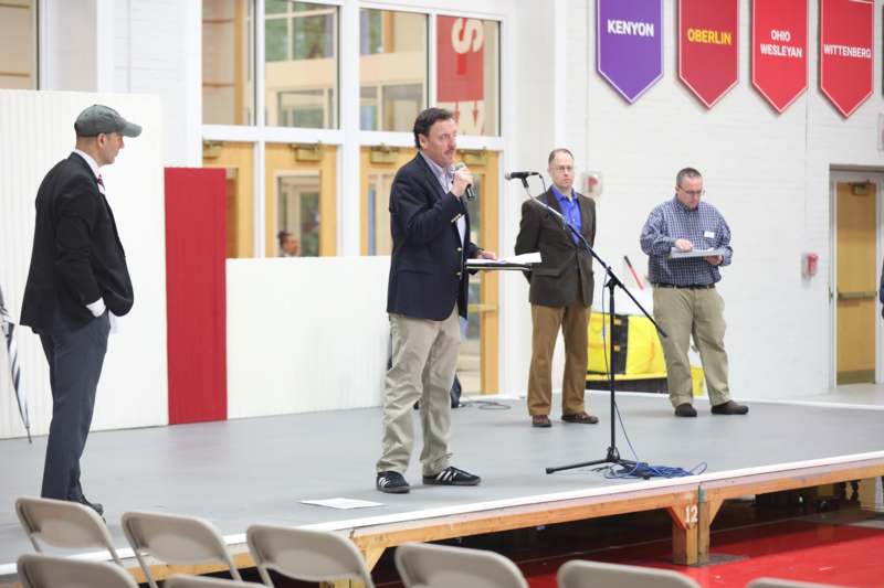a man speaking into a microphone on a stage with other people behind him