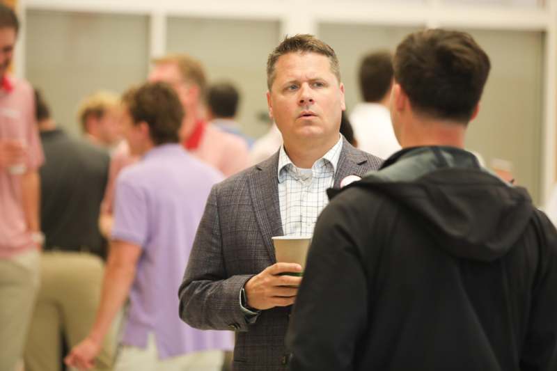 a man holding a cup and talking to another man