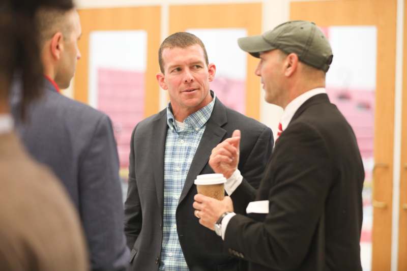 a group of men talking and drinking coffee