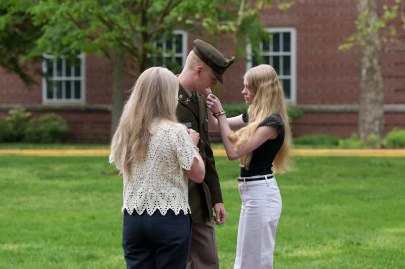 a man in a military uniform with two women standing in front of a brick building