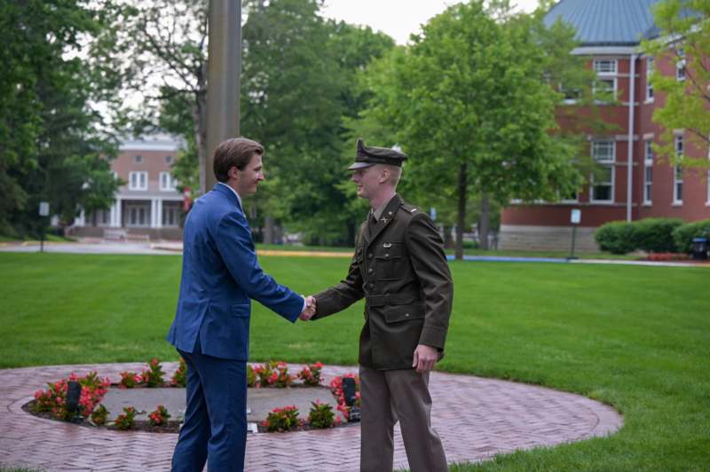 a man in a suit shaking hands with a man in a uniform