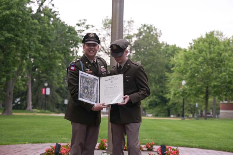 two men in military uniforms holding a certificate