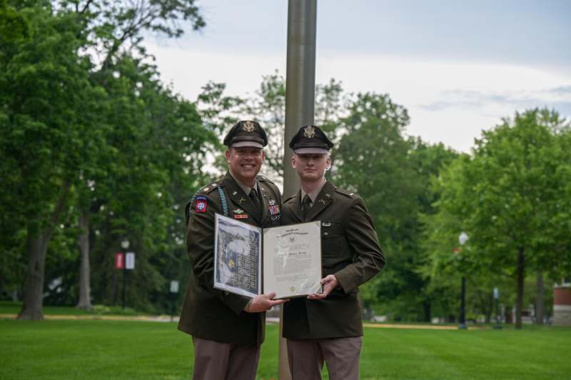 two men in military uniforms holding a certificate