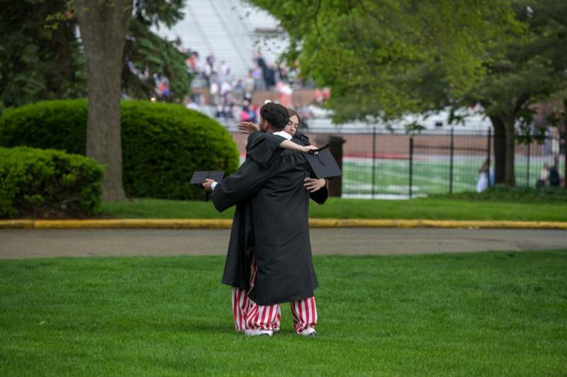 two men in graduation gowns hugging