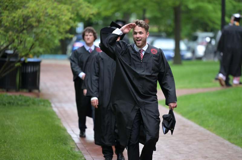 a group of men in graduation gowns saluting