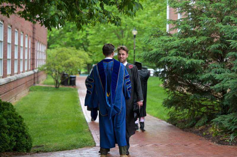 a man in a robe and gown walking down a sidewalk