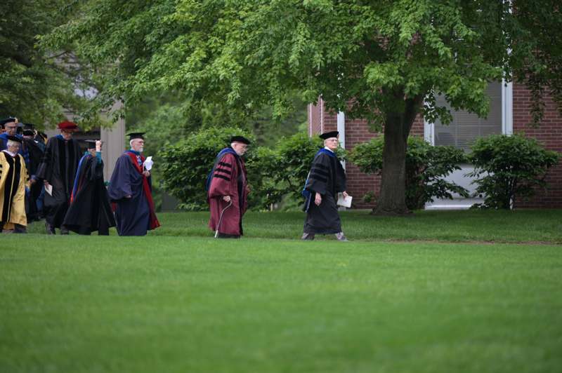 a group of people in graduation gowns walking on grass