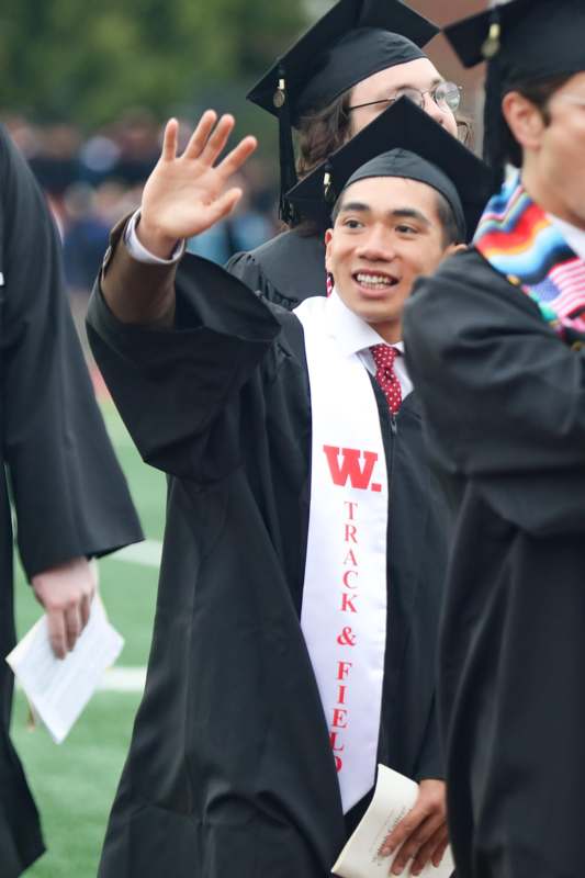 a man in a graduation gown waving