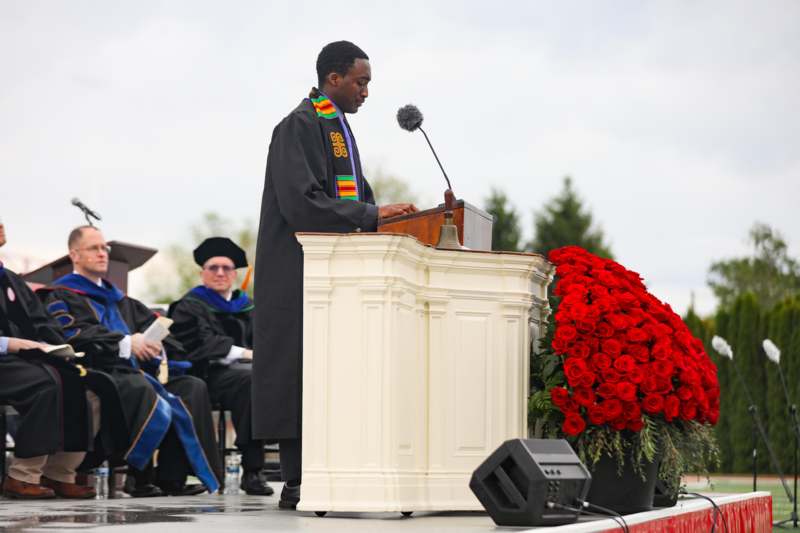 a man in a robe standing at a podium with a microphone
